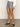 A person is shown from mid-torso down wearing Sanctuary Clothing™s voyage short yacht stripe, a blue and white pinstripe short, paired with a long-sleeve white shirt and black sandals on a gray floor against a light-colored wall.