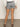 A person is seen from the back wearing Sanctuary Clothing's voyage short yacht stripe, a white jacket, and black sandals, standing on a concrete floor against a plain background.