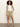 A woman with curly hair wears Sanctuary Clothing's white sleeveless top and liner short bamboo light olive green shorts, paired with black sandals, standing against a plain light background with one hand in her pocket.