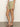 A person models Sanctuary Clothing's liner short bamboo in light khaki, paired with a white top and leopard print sandals. The photo, cropped from mid-torso to feet, is set on a gray floor against a plain light wall.