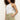 A person with curly hair wears the Sanctuary Clothing liner short bamboo, a white sleeveless top, and stands against a plain light wall with one hand in their pocket and a neutral expression.