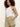 A person with curly hair wears the Sanctuary Clothing liner short bamboo, a white sleeveless top, and stands against a plain light wall with one hand in their pocket and a neutral expression.