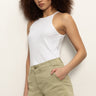 A person with curly hair wears the Sanctuary Clothing liner short bamboo, a white sleeveless top, and stands against a plain light wall with one hand in their pocket and a neutral expression.