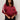 A woman with curly hair models the Sanctuary Clothing satin track jacket in crimson (extended sizing), featuring white sleeve stripes. She pairs it with dark pants and a black studded purse, posing against a light background.