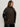 A woman models the Sanctuary Clothing club varsity jacket in midnight olive (extended sizing), featuring black faux leather sleeves and snap buttons, standing against a light background with one hand in her pocket.