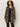 A woman with curly hair models the Sanctuary Clothing downtown jacket leopard mirage over a black blouse and pinstripe pants, standing against a plain light background.