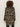 Seen from behind, a person with curly hair wears the Sanctuary Clothing downtown jacket leopard mirage€�featuring black, brown, and beige leopard print€�and black pants against a plain light background.