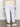 Someone wearing the rebel pant brilliant white from Sanctuary Clothing's inclusive collection stands facing away on a gray floor against a white wall.