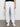 A person wearing Sanctuary Clothing's rebel pant in brilliant white, paired with white sneakers and a black top. Only the lower half of the body is visible, standing against a plain light-colored wall.