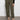 A person models the Sanctuary Clothing rebel pant hiker green cargo joggers, featuring side pockets, paired with black flat shoes; photo shows only the lower half of their body against a plain background.