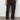 Wearing a white t-shirt, white sneakers, and Sanctuary Clothing's rebel pant obsidian cargo pants with elastic cuffs, a person stands against a plain, light-colored wall with hands in pockets.