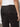 Close-up of a person wearing Sanctuary Clothing's rebel pant obsidian”black cargo pants with a button-flap back pocket and a small "Sanctuary" label. A silver ring is visible on the person's hand, paired with a white shirt.