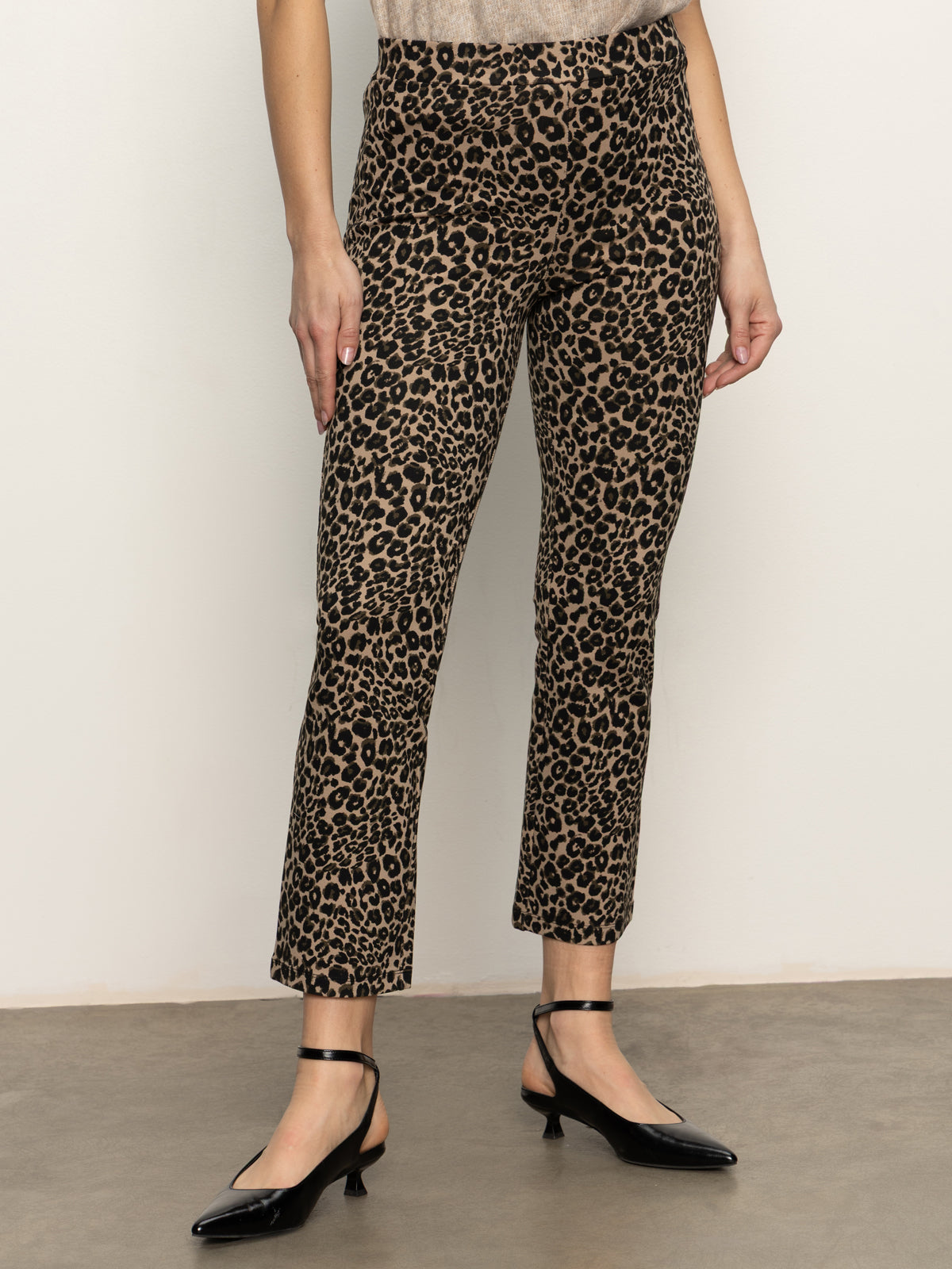 A person wears Sanctuary Clothing's carnaby kick crop leggings in french kitty print with black ankle-strap heels, standing against a neutral wall; only the body from shoulders down is shown.