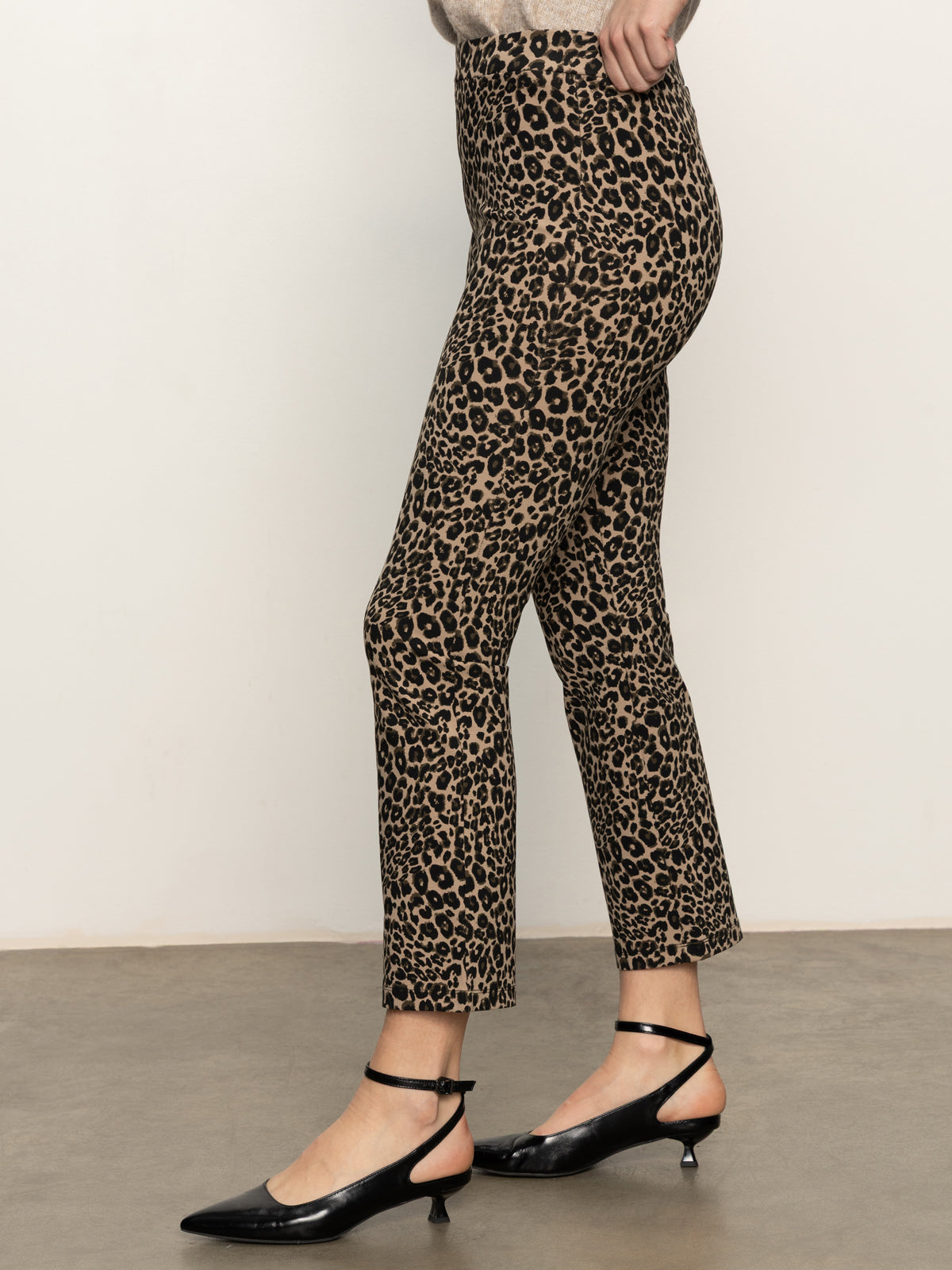 A person models Sanctuary Clothing's carnaby kick crop leggings in the french kitty print with black strappy kitten heels, standing on a brown floor against a plain light wall; only their lower half is visible.