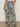 Someone wearing Sanctuary Clothing’s the soft trouser green oasis extended sizing, styled with black sandals and a tucked-in white top, stands against a plain background.