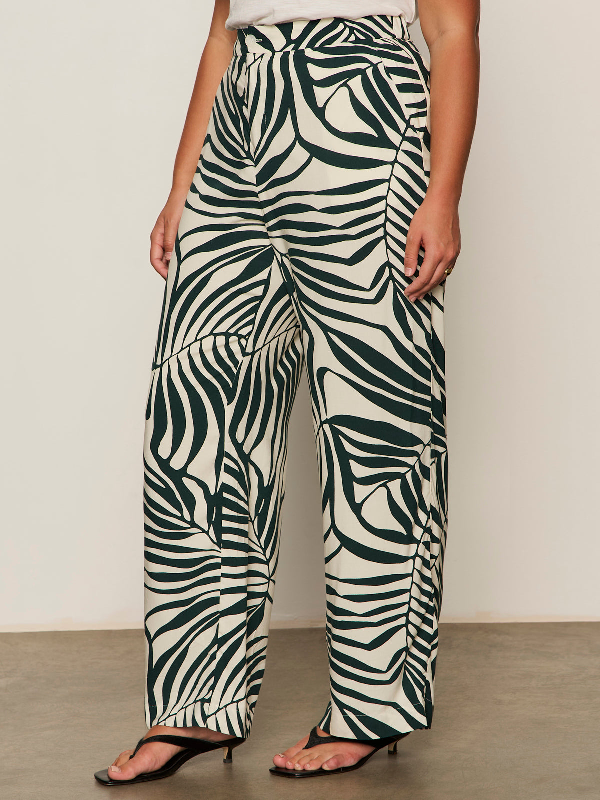 Someone wearing Sanctuary Clothing's the soft trouser green oasis (extended sizing) paired with black heeled sandals, standing against a plain background.