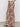 A person wearing Sanctuary Clothing„s the soft trouser desert bandana�high-waisted, wide-leg pants with a beige base and bold brown paisley print�stands sideways in black sandals against a plain background.