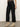 Wearing Sanctuary Clothing's the marine jeans after hours�a pair of wide-leg black jeans�a person stands on a concrete floor against a plain, light-colored background.