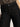 Close-up of a person wearing Sanctuary Clothing's the marine jeans after hours, high-waisted black denim with large front pockets, styled with a tucked-in leopard print top. Only the lower torso and part of one arm are visible.