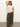 A person poses confidently in Sanctuary Clothing's Linen Marine Wide Leg Pant from the Kalamata Inclusive Collection, wearing a sleeveless cream crochet top. They stand against a plain background, one arm raised, the other in their pocket, wearing sandals and minimal jewelry.