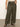 A person in Sanctuary Clothing's Linen Marine Wide Leg Pants (Kalamata) from the Inclusive Collection, paired with a sleeveless white textured top, black sandals, and a gold bracelet stands against a neutral background.