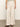 A person is wearing the Sanctuary Clothing linen marine wide leg birch pants in cream with front pockets, standing on a concrete floor. They have a partially visible striped top at the waist and brown sandals against a neutral wall backdrop.