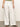 A person is wearing Sanctuary Clothing's "the linen marine wide leg white" paired with a green top and brown sandals, set against a light-colored wall.