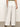 A person is standing with their back to the camera, wearing a green top and Sanctuary Clothing's "the linen marine wide leg white" pants featuring back pockets. They have dark sandals on, standing on a neutral-toned floor against a light background.