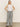 A woman with long, straight blonde hair stands against a plain background wearing Sanctuary Clothing's marine full length semi high rise pant in yacht stripe. Her hands rest on her hips and she's paired the pants with a sleeveless white top and black sandals.