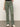 A person is wearing Sanctuary Clothing's sculpted Hayden bootcut pants in dark spruce and white sneakers, standing against a plain background. The pants feature multiple pockets and a fitted waistband. The upper body is out of the frame.
