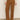Someone wearing Sanctuary Clothing's corduroy marine pant in bronze, paired with a light beige long-sleeve top and cream heeled boots, stands against a plain background.