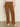A person wearing Sanctuary Clothing's corduroy marine pant in bronze, paired with a beige long-sleeve top and off-white heeled boots, stands against a plain background.