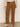 A person faces away from the camera against a neutral background, wearing Sanctuary Clothing’s corduroy marine pant in bronze, paired with a beige long-sleeve top and cream heeled boots.