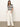 A person is against a white background wearing a black and white striped v-neck top with short sleeves, paired with Sanctuary Clothing's arden wide-leg jeans in bleached white pinstripe. They have their hands in the jeans' pockets.