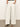 A person wears cream-colored, wide-leg jeans with thin pinstripes from Sanctuary Clothing called "arden wide leg jeans bleached white pinstripe." Their hands are in the pockets. They also have on black strappy sandals against a neutral light background.
