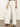 A person is wearing Sanctuary Clothing's arden wide leg jeans in bleached white pinstripe with a black top and sandals. Their hand rests on their hip against a plain white background.
