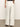 A rear view shows someone wearing Sanctuary Clothing's arden wide-leg jeans in bleached white pinstripe. These high-waisted jeans feature two large back pockets and thin vertical stripes, as the person stands on a neutral-colored floor.