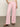 Person in Sanctuary Clothing's arden wide leg jeans in washed cherry blossom stands with one hand in their pocket against a neutral background, wearing a crocheted top and brown sandals.