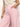 A person is wearing a Sanctuary Clothing white crochet top and arden wide leg jeans in washed cherry blossom. Their left hand is in the pocket, and a gold bracelet adorns their wrist against a plain white background.