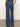 A person wearing Sanctuary Clothing's arden wide leg jeans in Perfect Storm stands on a polished concrete floor, facing away to show the two large back pockets.