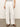 A person stands on a smooth, neutral-colored floor, wearing Sanctuary Clothing's Hopper Straight Leg Cargo pants in bleached white, paired with a striped shirt and brown sandals. Their hands rest by their sides.