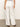 A person wearing Sanctuary Clothing's Hopper Straight Leg Cargo in bleached white is seen from the rear. They're styled with a tucked-in striped top and brown heeled shoes, all set against a plain, light-colored background.