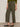 A person wears Sanctuary Clothing's boyfriend utility pant kalamata—olive green, high-waisted cargo pants with patch pockets—paired with a green sweater and black slingback flats, standing against a plain background.