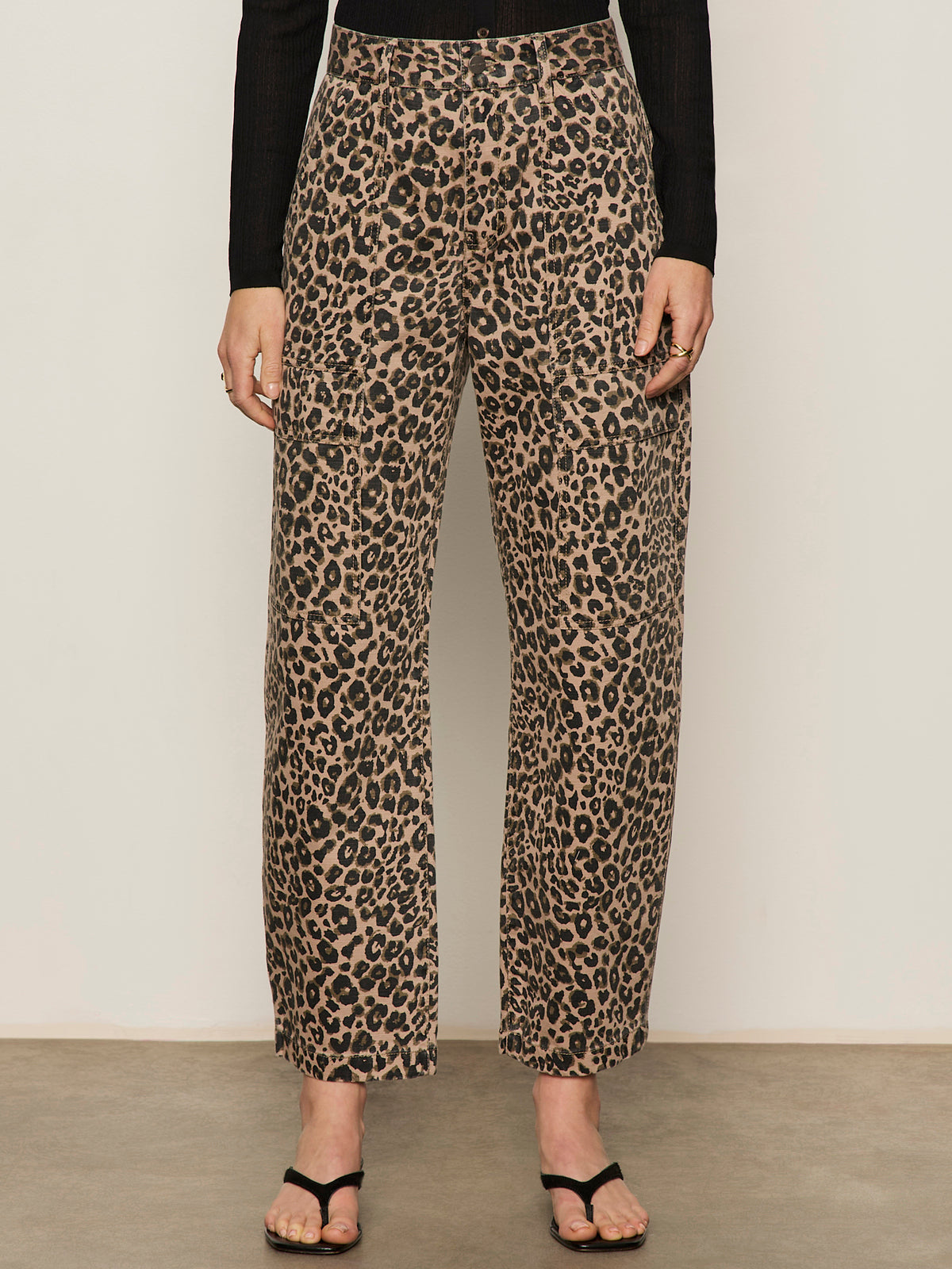 A person models the Sanctuary Clothing boyfriend utility high rise pant in French Kitty, styled with a black long-sleeve top and black sandals; shown from the shoulders down against a plain background.