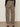 A person stands on a concrete floor wearing Sanctuary Clothing's boyfriend utility high rise pant in French Kitty, paired with a black long-sleeve top and black heeled sandals. The photo captures the back view of the outfit.