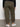 Person wearing Sanctuary Clothing's sahara tapered pant in burnt olive from the inclusive collection, paired with a black long-sleeve top and white sneakers, standing indoors facing away from the camera.