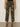 A person models the Sanctuary Clothing rio pant rambler camo cargo pants with black heeled sandals, standing against a beige background with arms relaxed at their sides and upper body not shown.