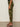 A person stands sideways against a plain background wearing Sanctuary Clothing’s rio pant rambler camo, styled with black heeled sandals.