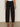 A person wearing Sanctuary Clothing's polished barrel pant in black with black heeled sandals, standing against a light wall and concrete floor. Only the lower half of the body is visible.