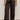 A person wearing Sanctuary Clothing's modern satin trouser in black (extended sizing), paired with a white button-up shirt and black pointed-toe heels, stands against a plain background.
